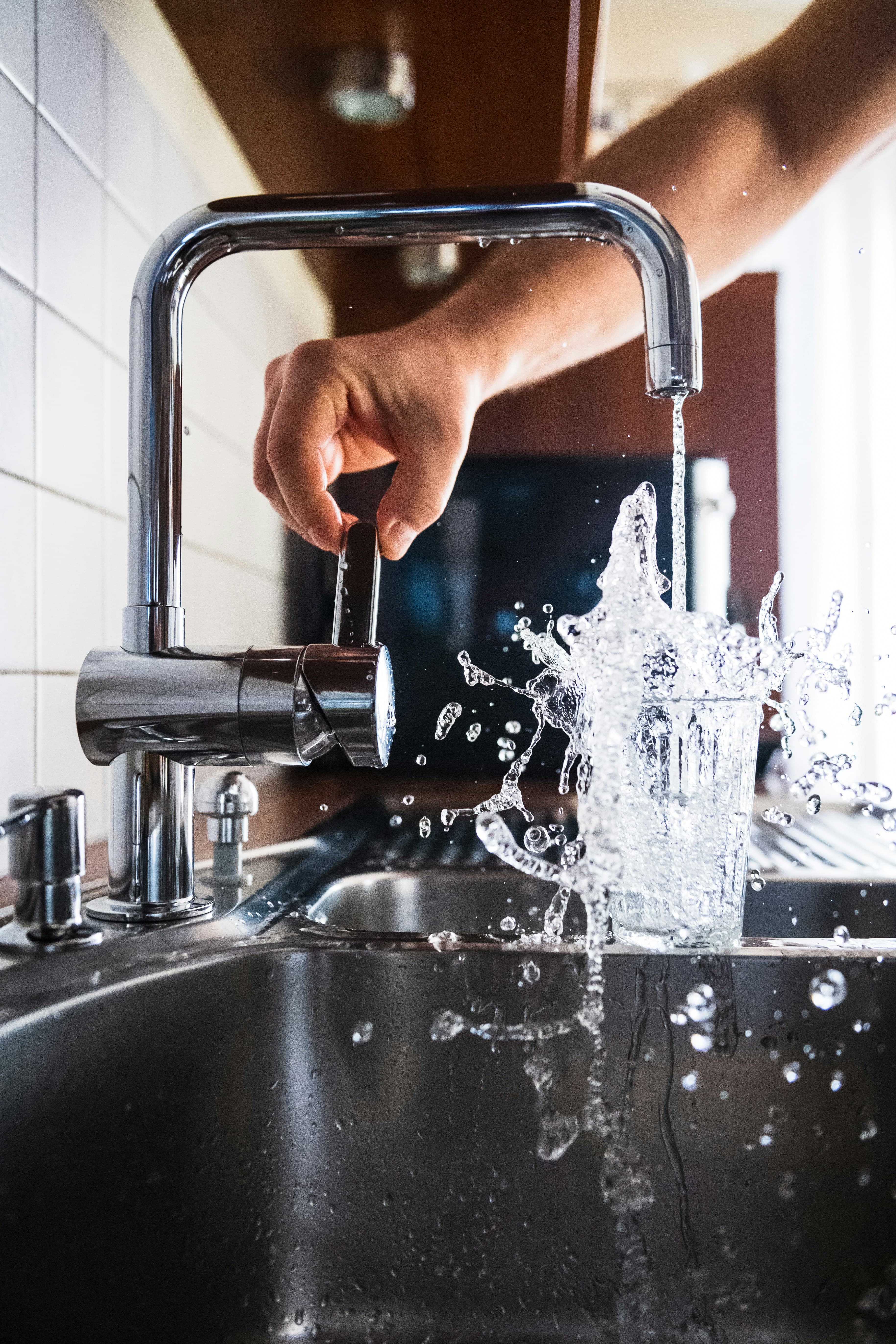 Water splashing into a glass — drinking water contaminants guide
